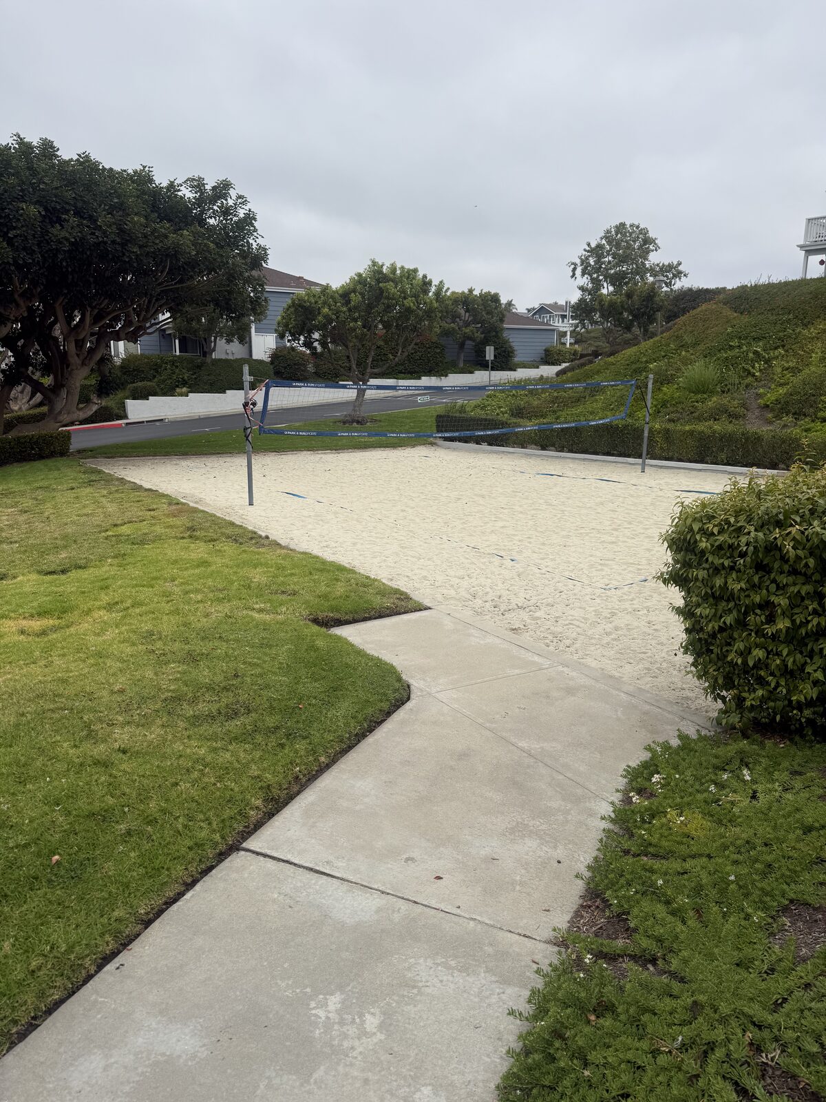 The community sand volleyball court, mostly empty, beside the pool